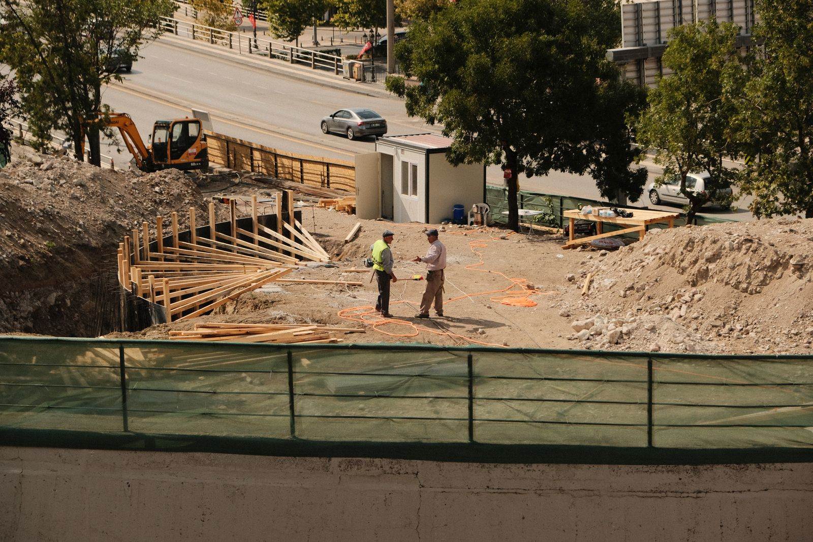 Two engineers discussing plans at an active construction site under sunny skies